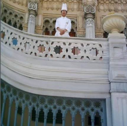 A young chef on the marble balcony of a historic building.
