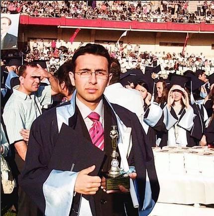 In graduation gown, holding the first-place trophy.